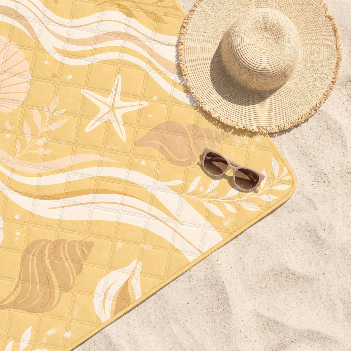 Close-up of the Yellow Feeling Sunny quilted beach blanket on sand with a sun hat and sunglasses