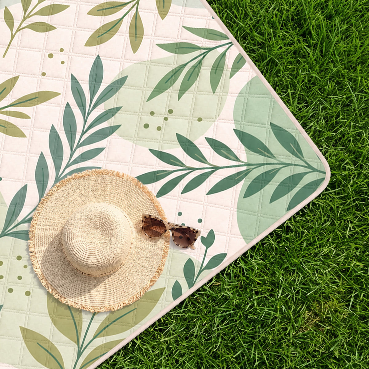 Sage Bentoria padded picnic blanket on grass with a sun hat and sunglasses